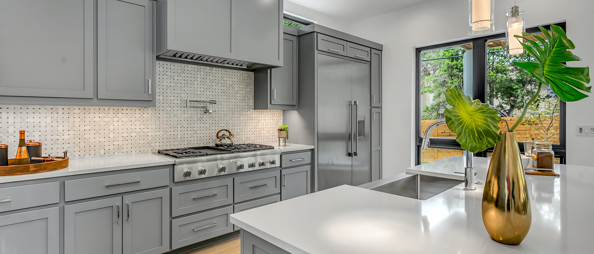 Gray kitchen with light stone countertops and white tile backsplash