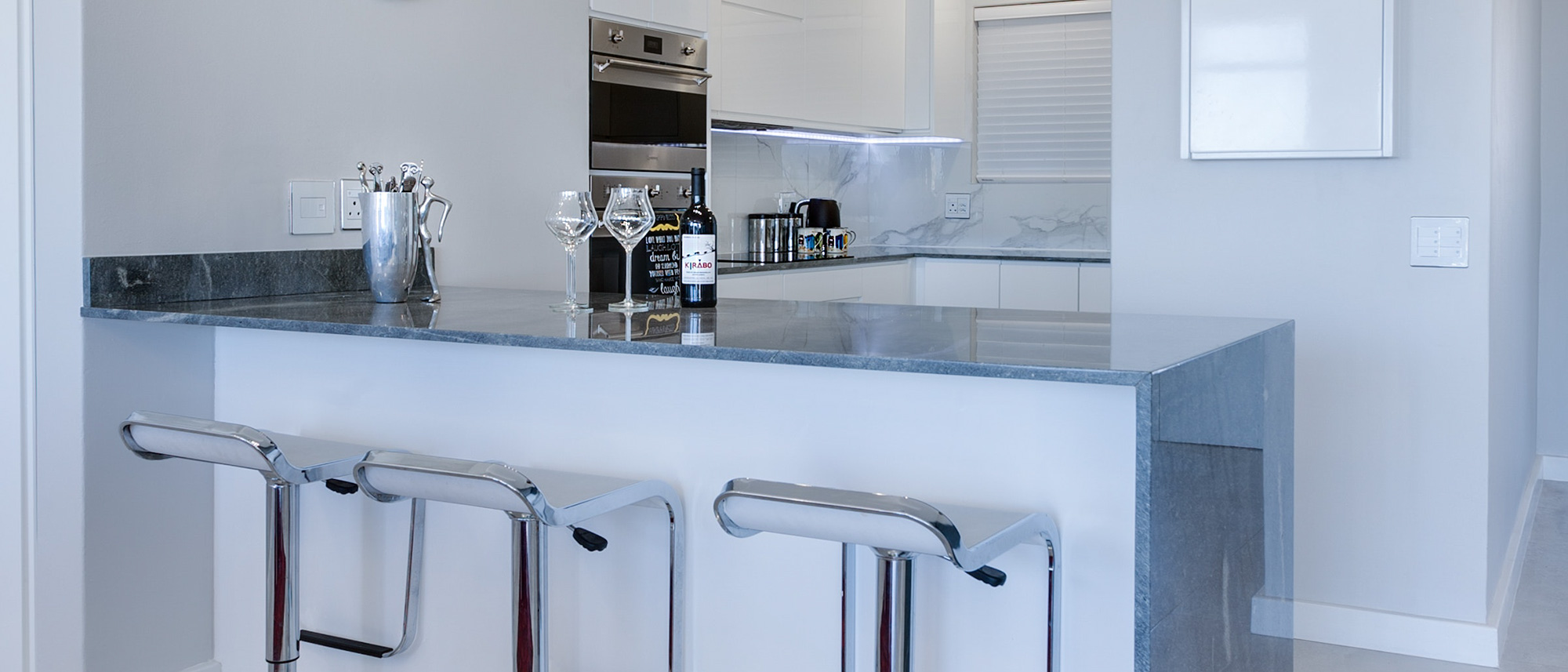 Kitchen peninsula with a dark stone countertop and bar stools